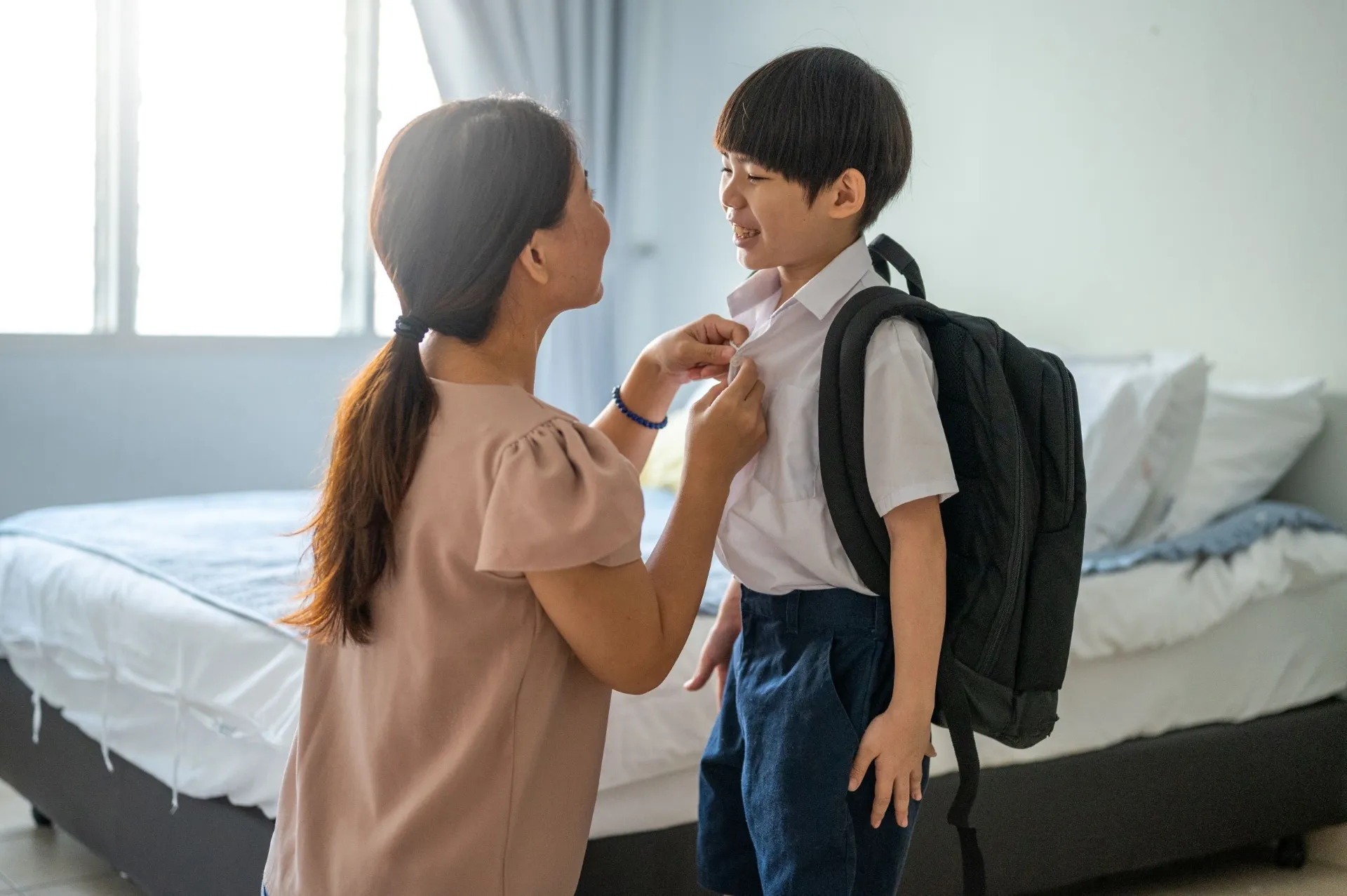 A mother helps her son get ready for school.